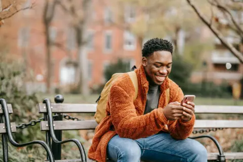 Happy man sitting in the park booking QuickMD appointment