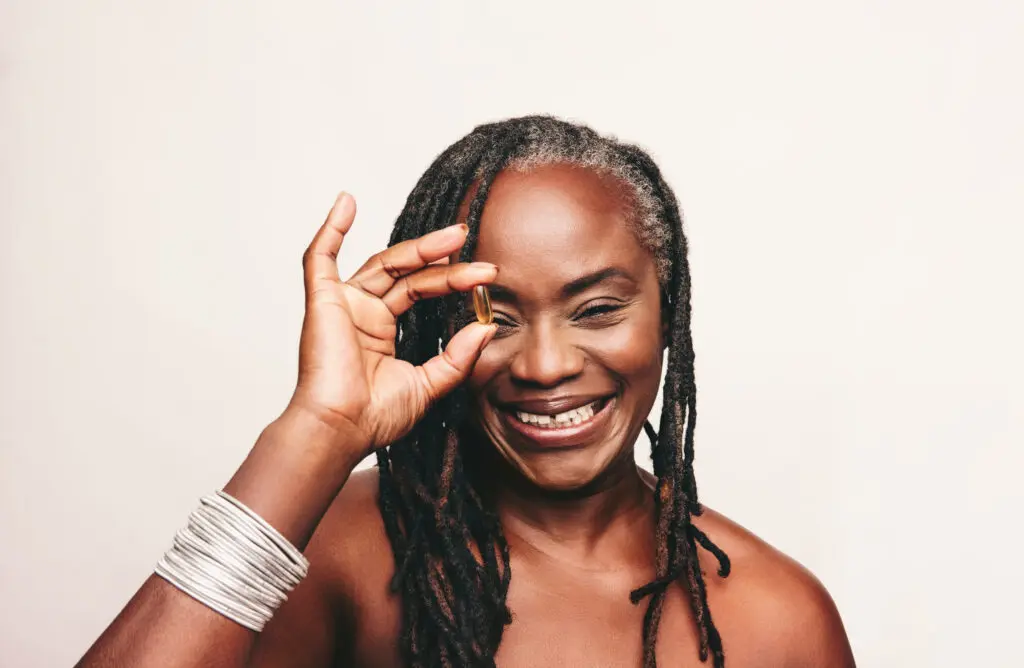 Cheerful woman holding a pill she received from QuickMD Urgent Care Services