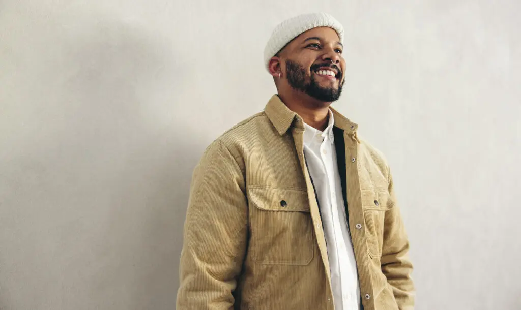 happy young man smiling in front of a gray wall