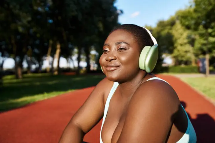 African American woman smiling on track and field arena during online weight loss treatment