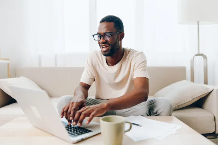 Smiling African American man on couch receiving online healthcare services