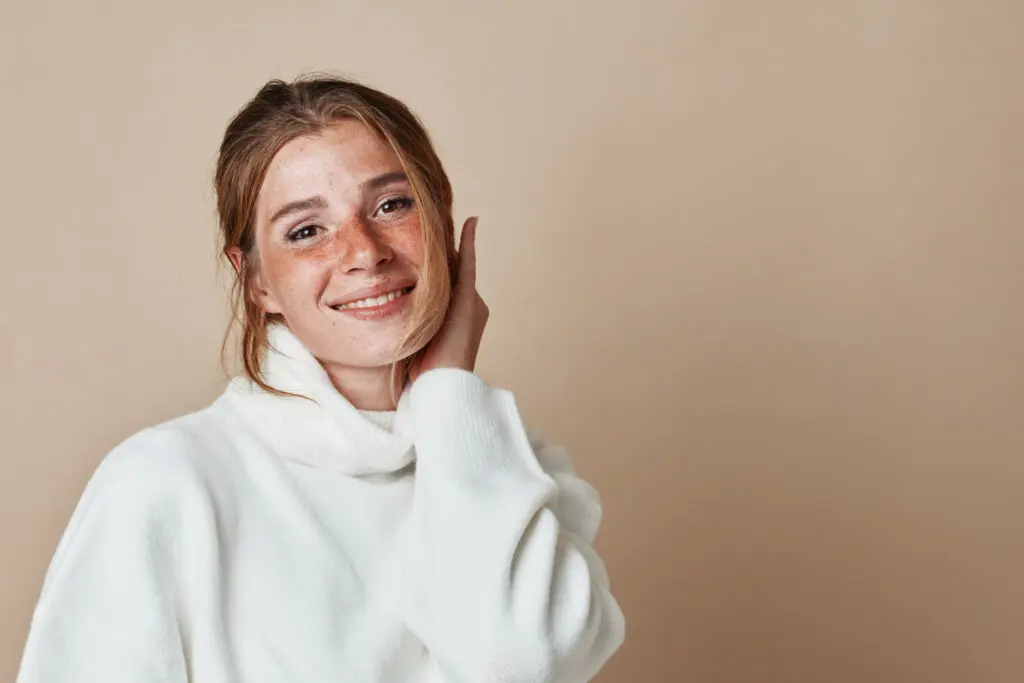 young woman with freckles smiling after receiving urgent care services