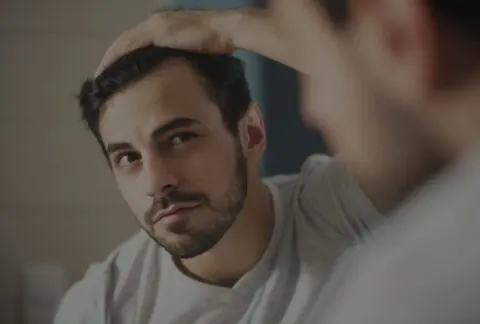 Man looking in mirror at his male pattern baldness