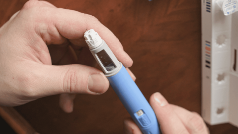 Close-up of a person holding a blue Ozempic injection pen