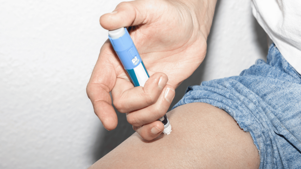 A person administering an Ozempic injection into their thigh using a blue injection pen