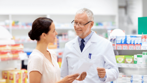 Pharmacist discussing prescription with a female customer in a pharmacy