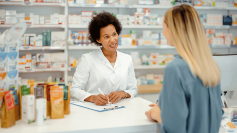 Pharmacist explaining how to find cheaper brand-name Ozempic to a customer at a pharmacy counter