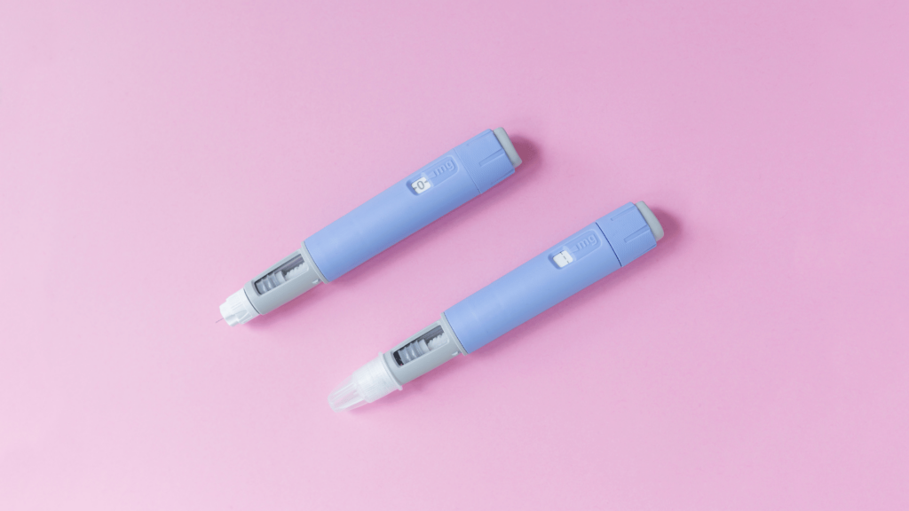 Two Ozempic injection pens on a pink background