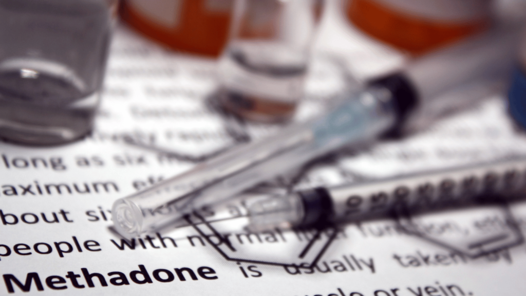 Syringes and medication vials on a document with the word 'Methadone' in focus