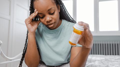 Woman experiencing Subutex side effects while holding a medication bottle