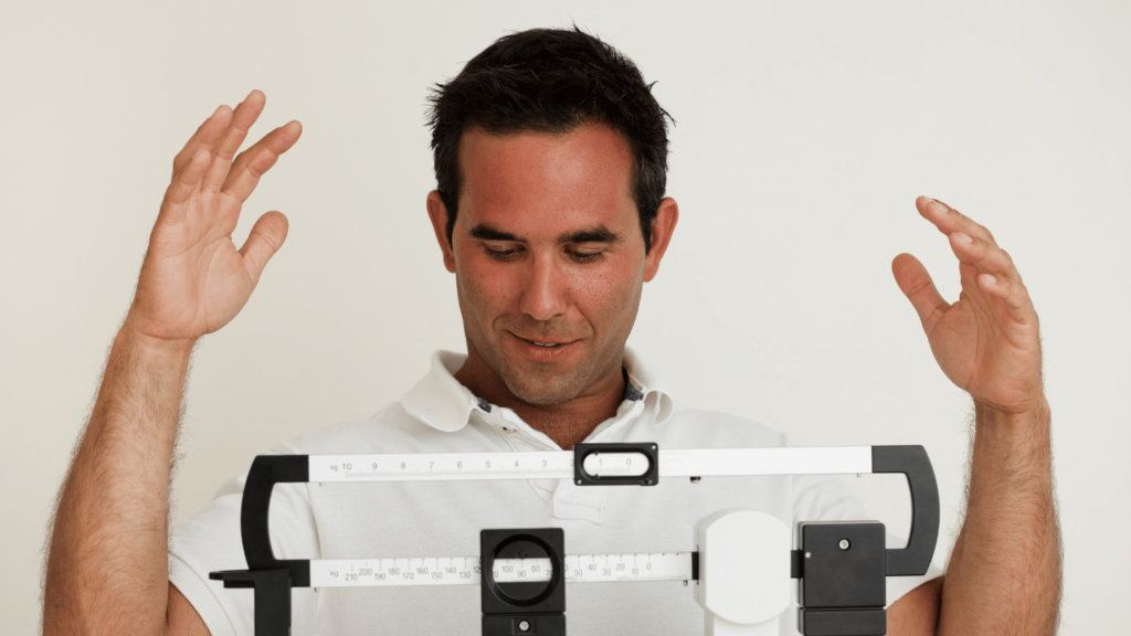 Man excitedly tracking weight loss progress on a scale