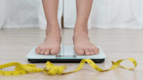 Person standing on a scale with a measuring tape on the floor