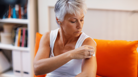 Woman applying a transdermal patch