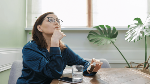 Woman holding a medication bottle while contemplating