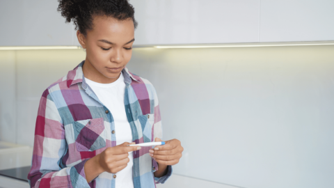 Woman with OPUD holding pregnancy test