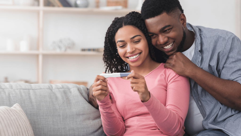 Smiling couple holding a positive pregnancy test, discussing planning for parenthood and Suboxone treatment options before pregnancy