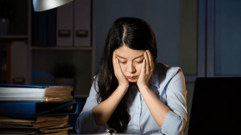 Tired woman sitting at a desk with her head in her hands, struggling to stay awake, representing Suboxone-related drowsiness and fatigue management