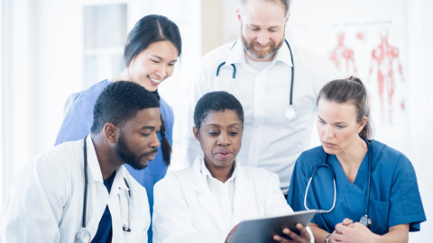 A team of medical professionals reviewing information together on a tablet, representing the collaborative approach behind Journavx, a promising treatment offering pain relief without addiction risks