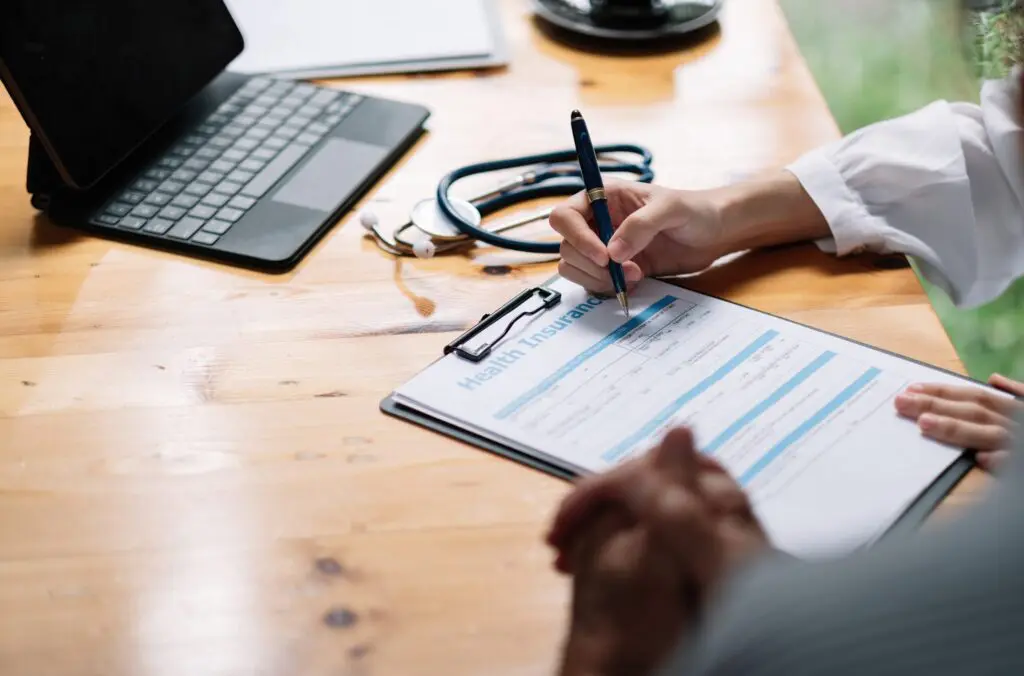 Female health insurance broker presenting insurance benefits to a businessman to fill out insurance.