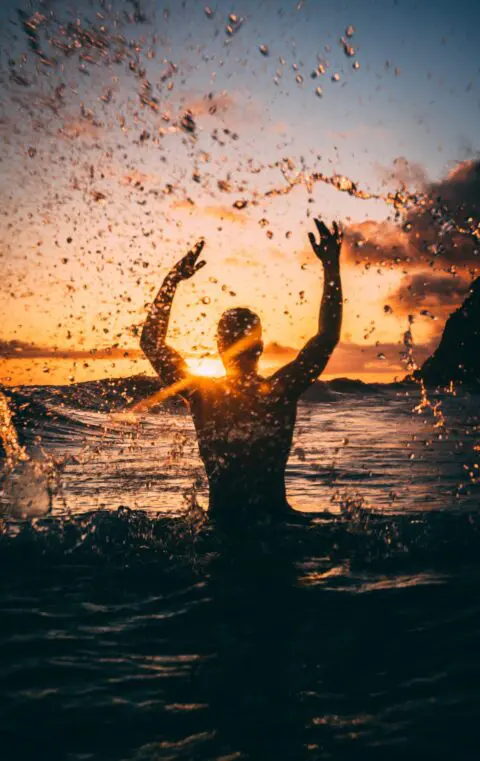 Man outside raising his arms after a successful treatment of bipolar disorder and depression from QuickMD's telehealth counseling services