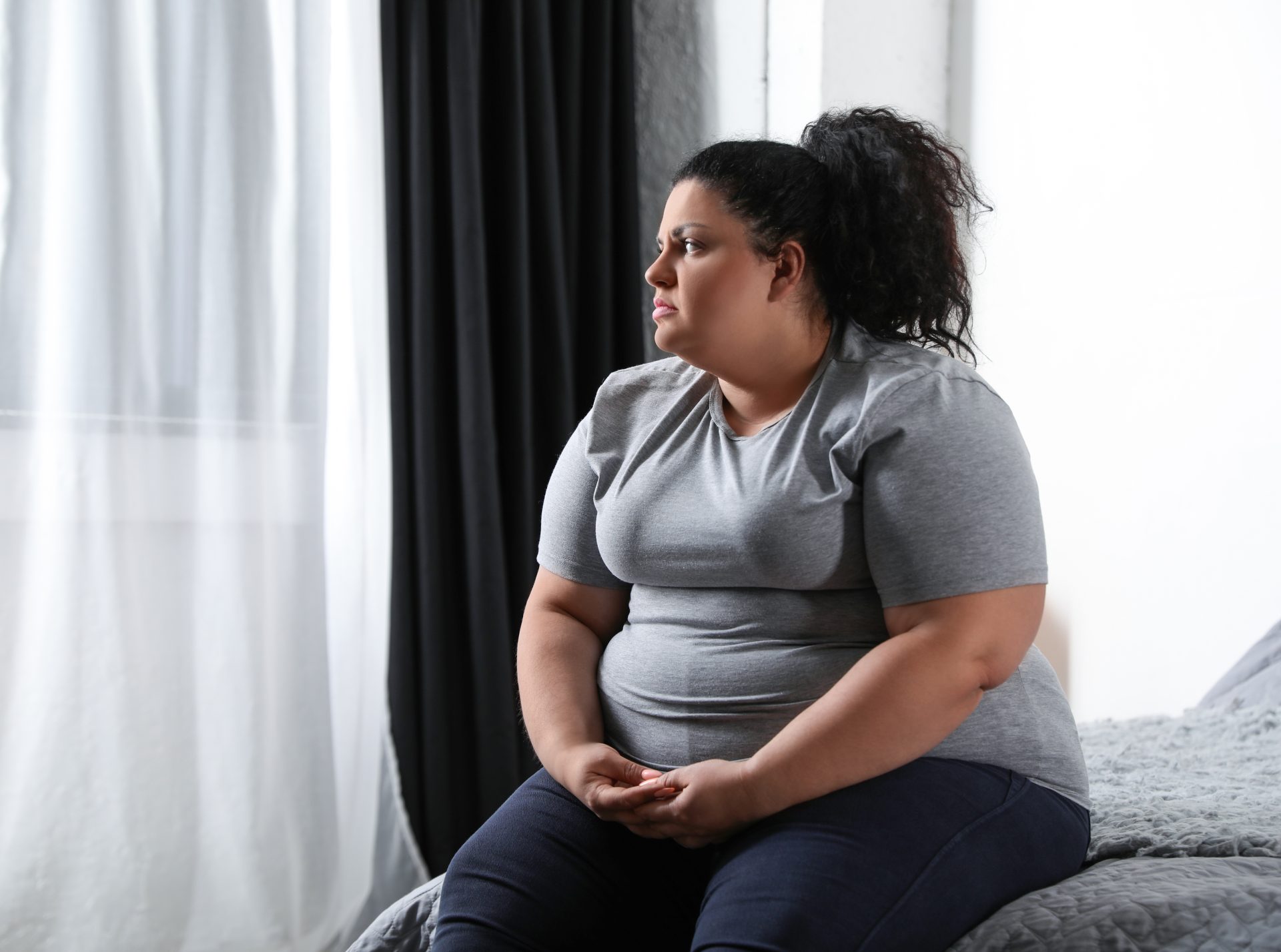 Overweight woman looking sad on a bed