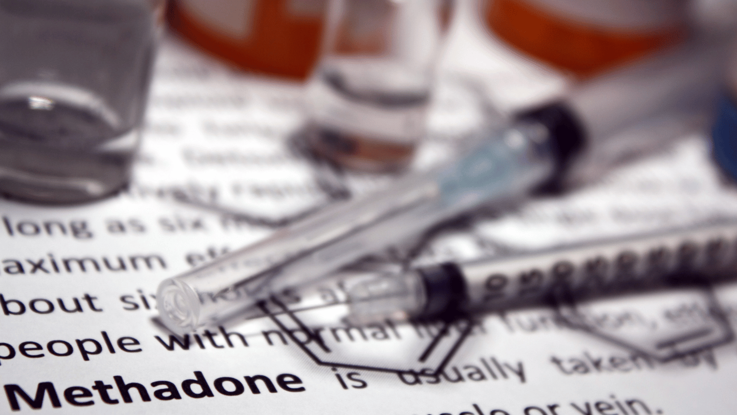 Syringes and medication vials on a document with the word 'Methadone' in focus, representing the use of suboxone vs. methadone in opioid addiction treatment