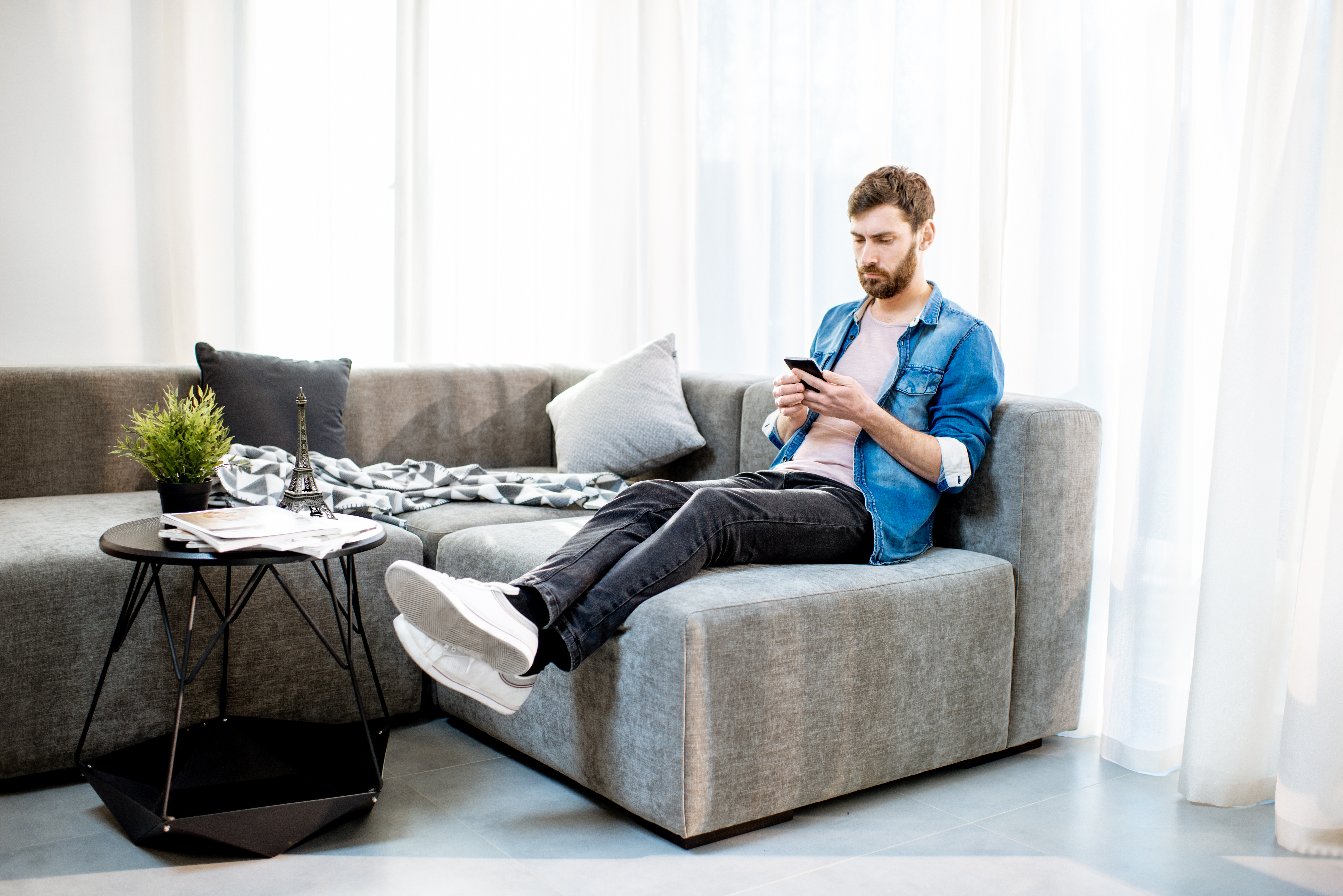 Man on the couch using phone at home