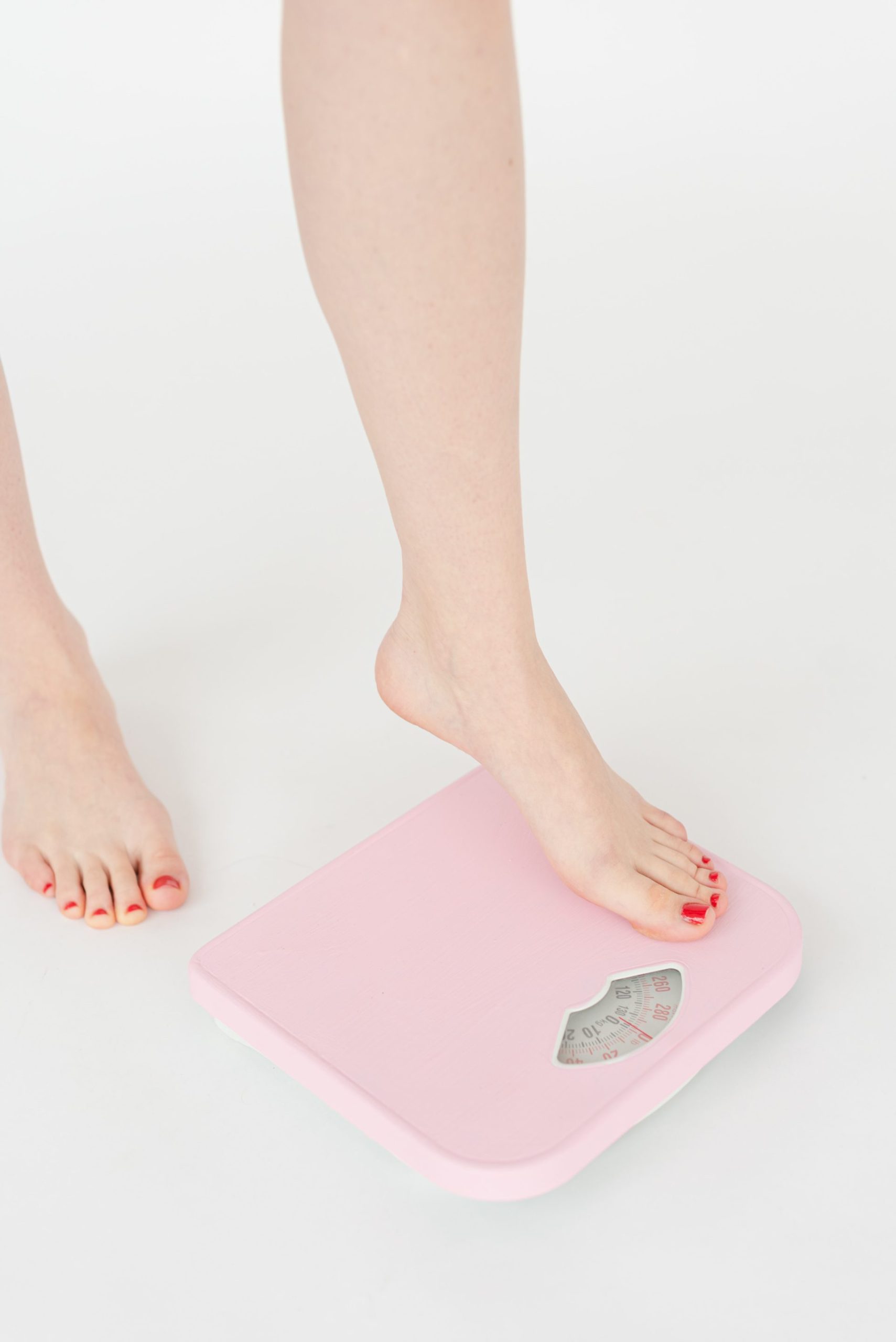 Woman stepping on a scale after taking Mounjaro prescribed for weight loss