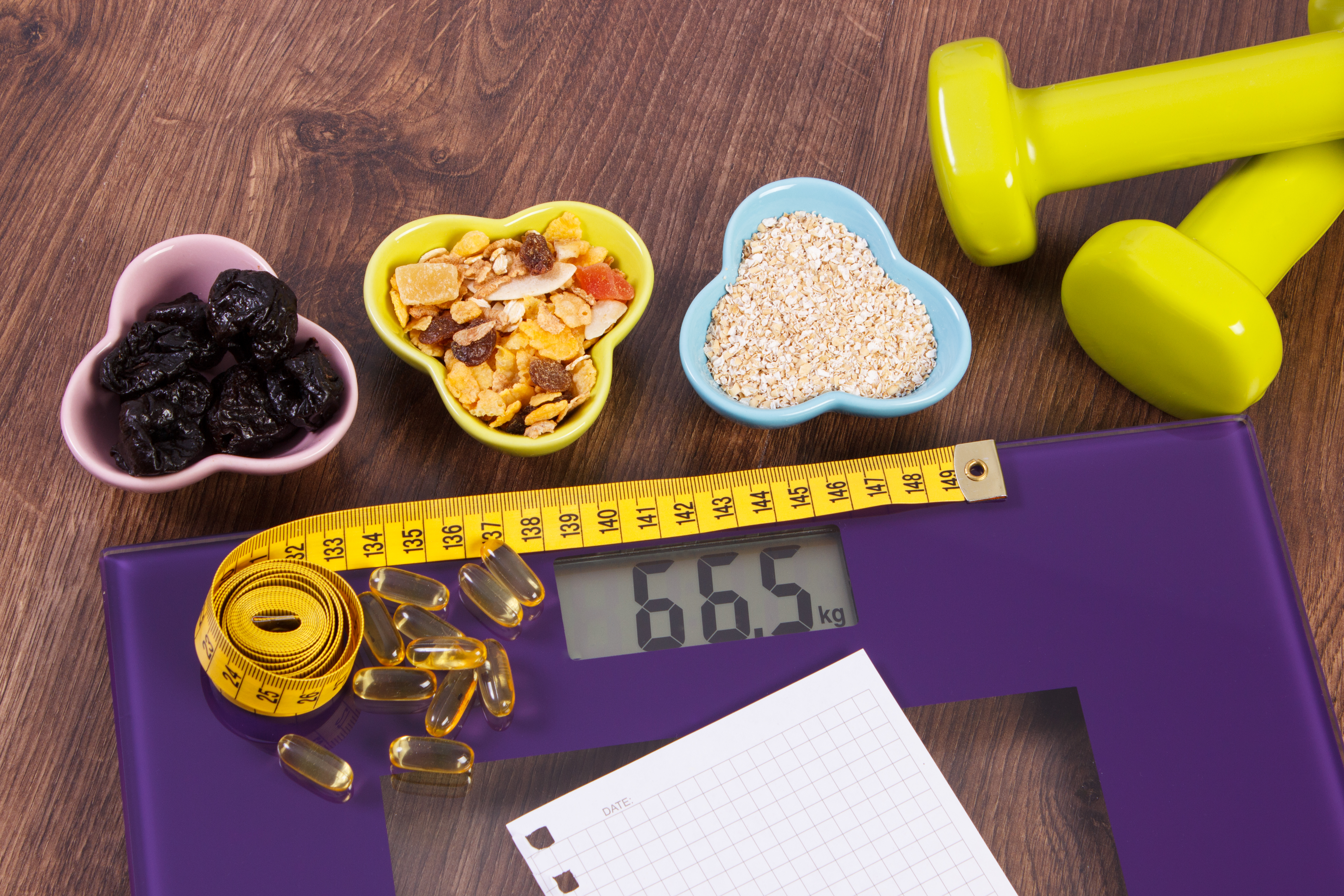 Tape measure on digital scale, tablets, dumbbells and muesli, healthy food and slimming concept