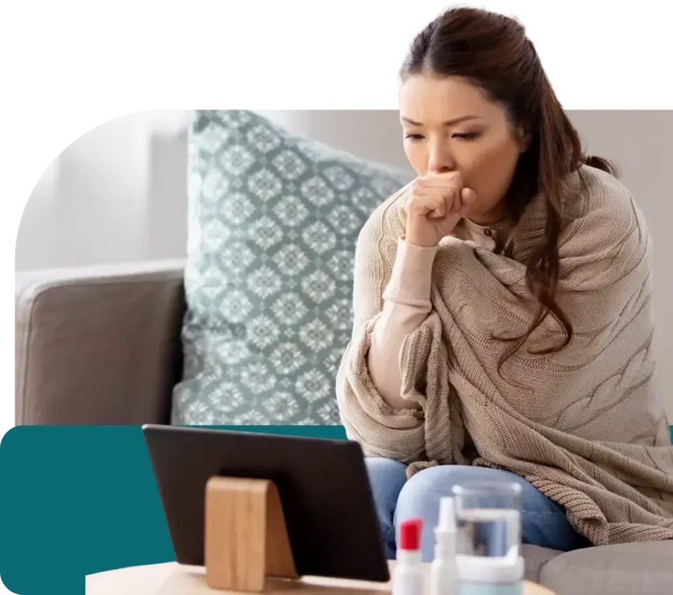 sick woman sitting on a couch speaking to a telehealth provider at QuickMD